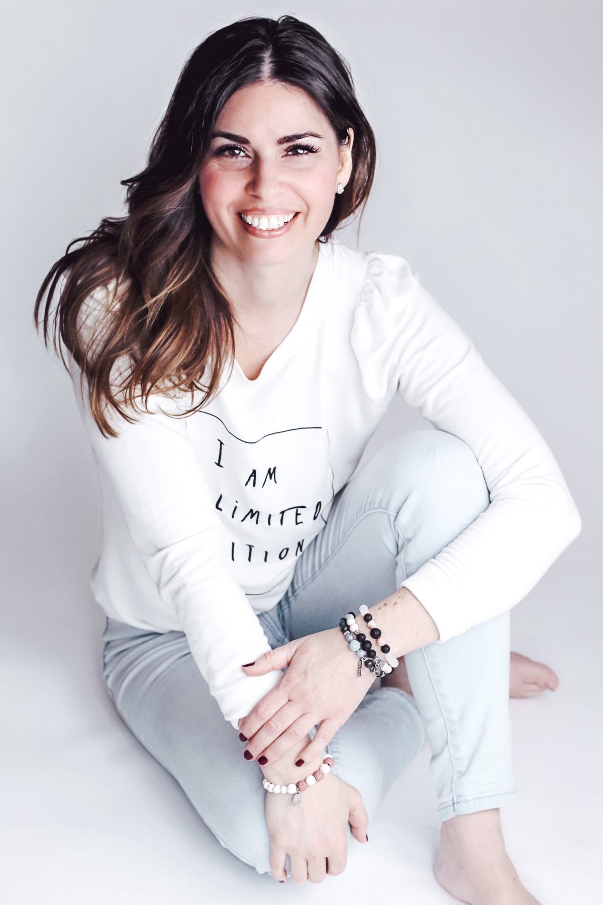 Begin Again's CEO, Carrie Lynn, smiling for the camera and wearing a white t-shirt.